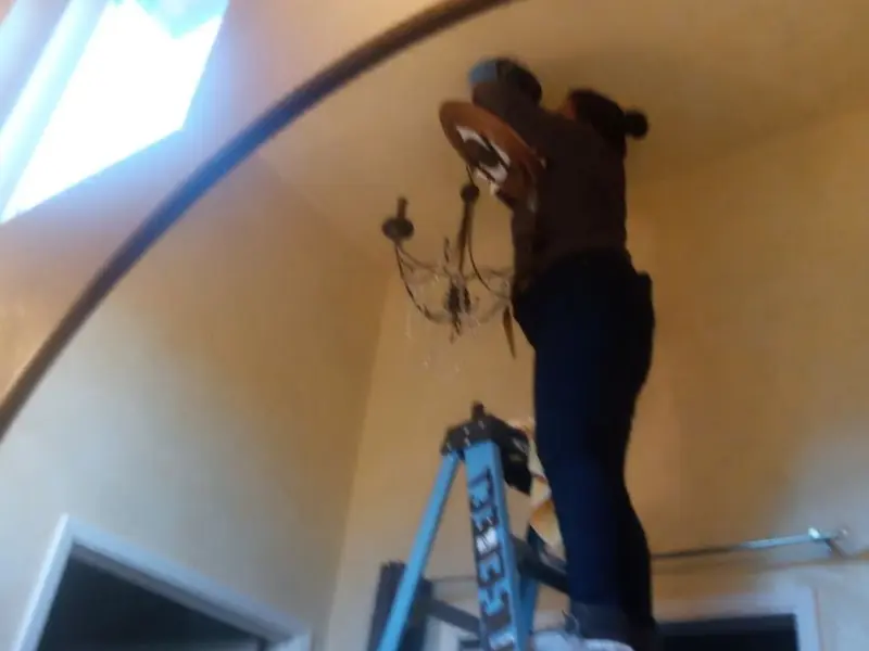 Electrician installing a chandelier in a Allen residence